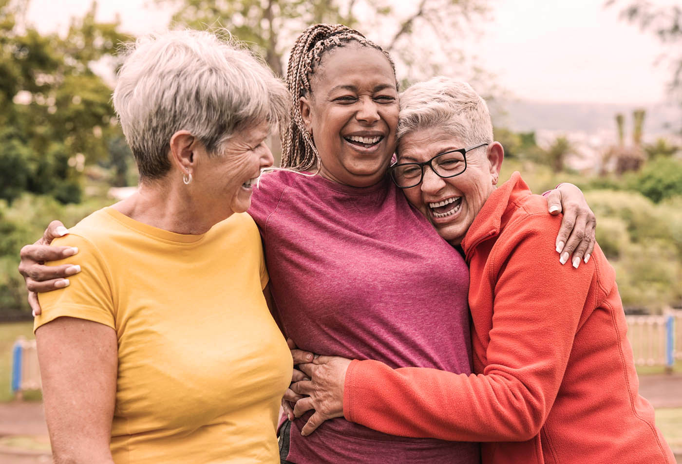 A group of elderly women laughing and hugging each other - discover Littleton multiple sclerosis pain treatment today.