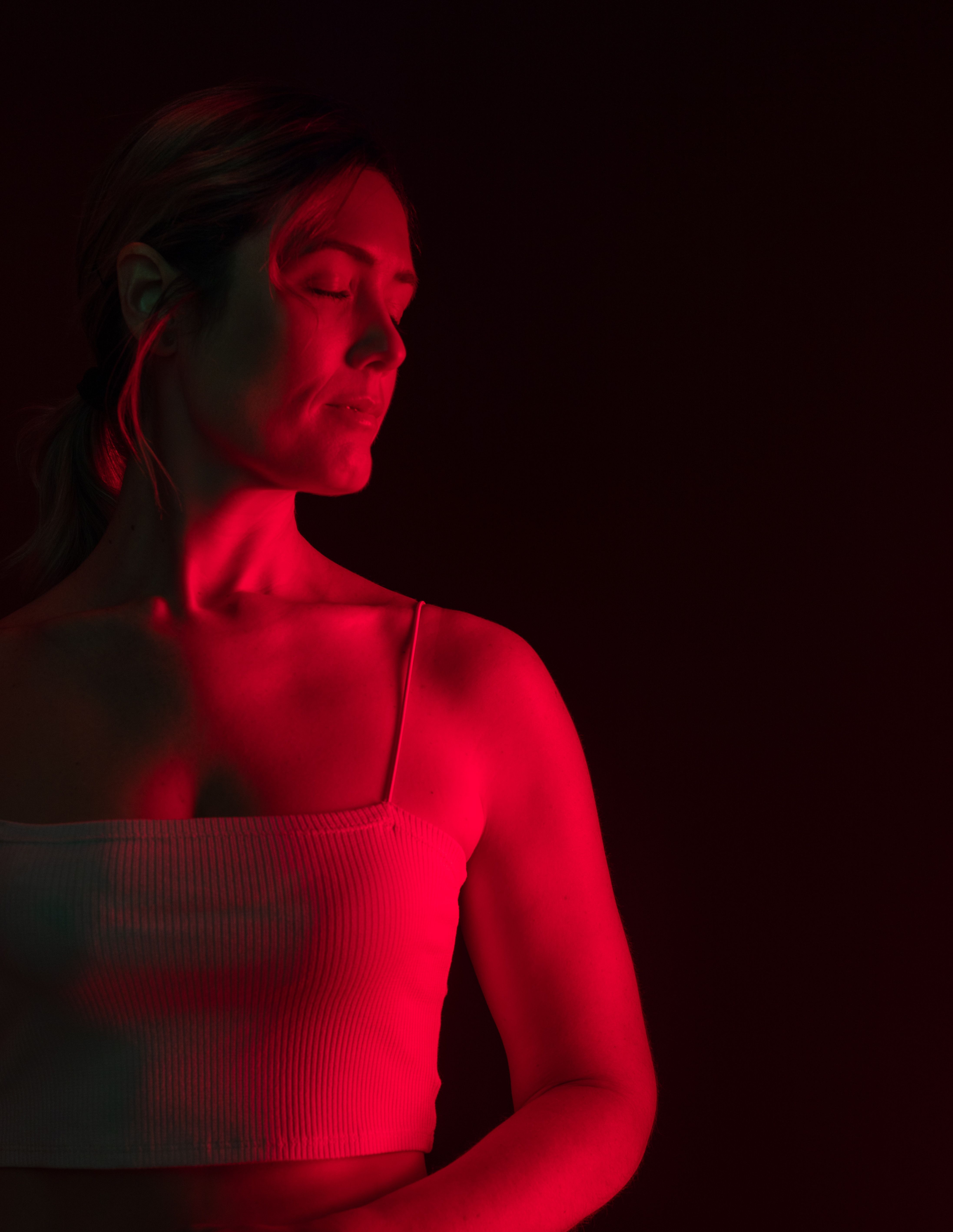 A woman standing in red light - experience what a photofacial can do for you.