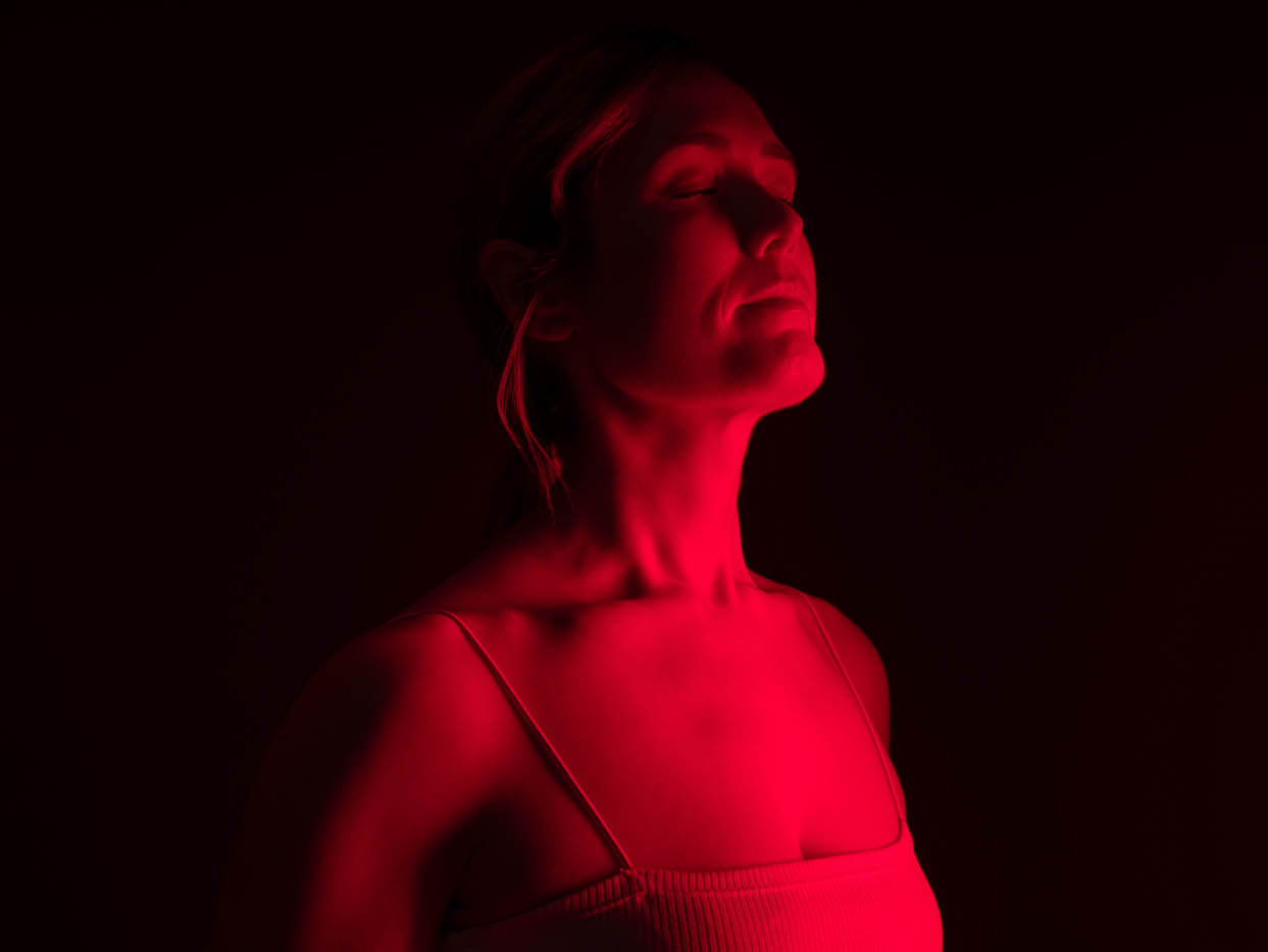 A woman standing in red light - learn about the alternative that Light Lounge brings if you are looking for pain management specialist in Holland, MI.