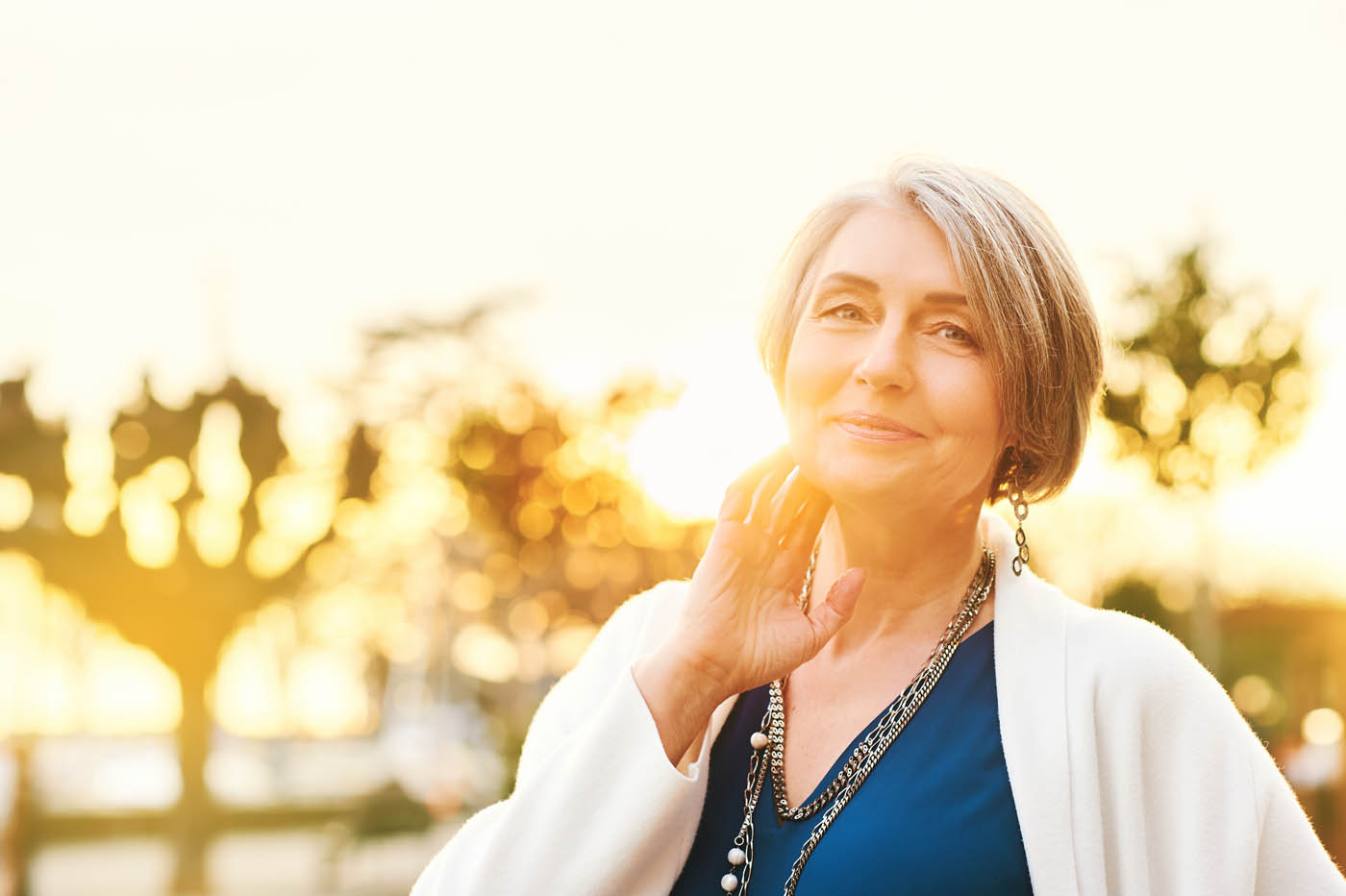 An woman with radiating skin in her late 40s standing in front of a sunset, learn the benefits of getting a photofacial in Denver, CO.