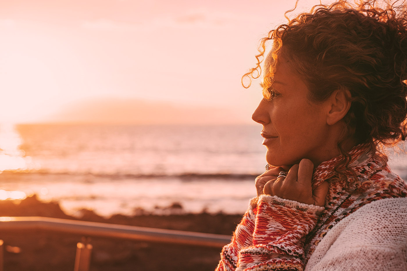 An women with radiating skin in her late 40s standing in front of a sunset, learn the benefits of our photofacial in Denver.