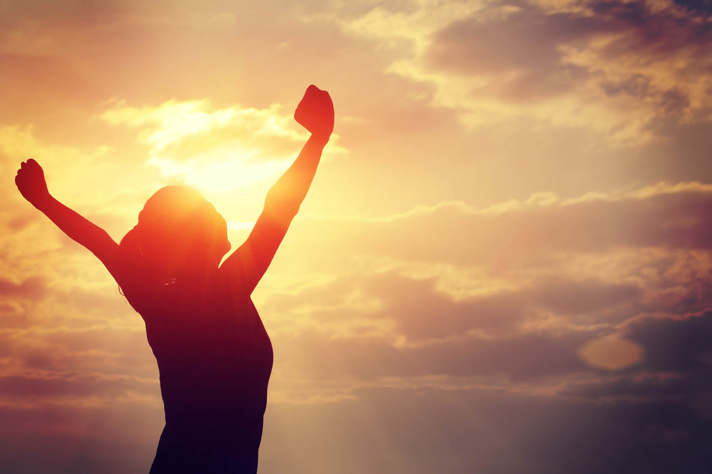 A woman standing in the light with her arms up in the air - learn how you can get relief with Light Lounge's back pain management in Lehi, UT.